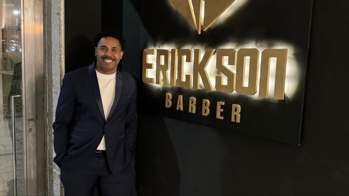 Erickson Barber em frente ao letreiro da barbearia