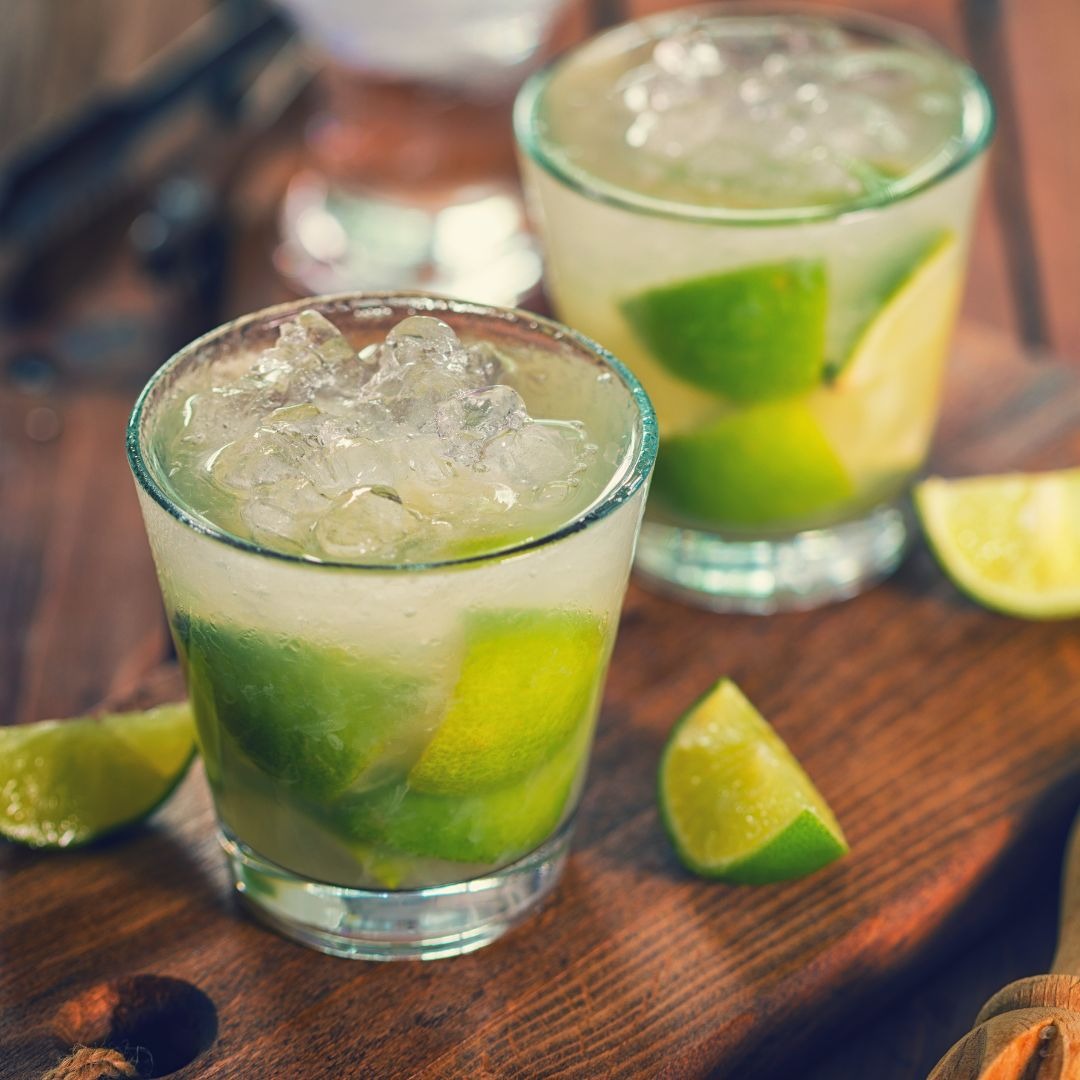 Caipirinhas de lima sobre t&aacute;bua de madeira